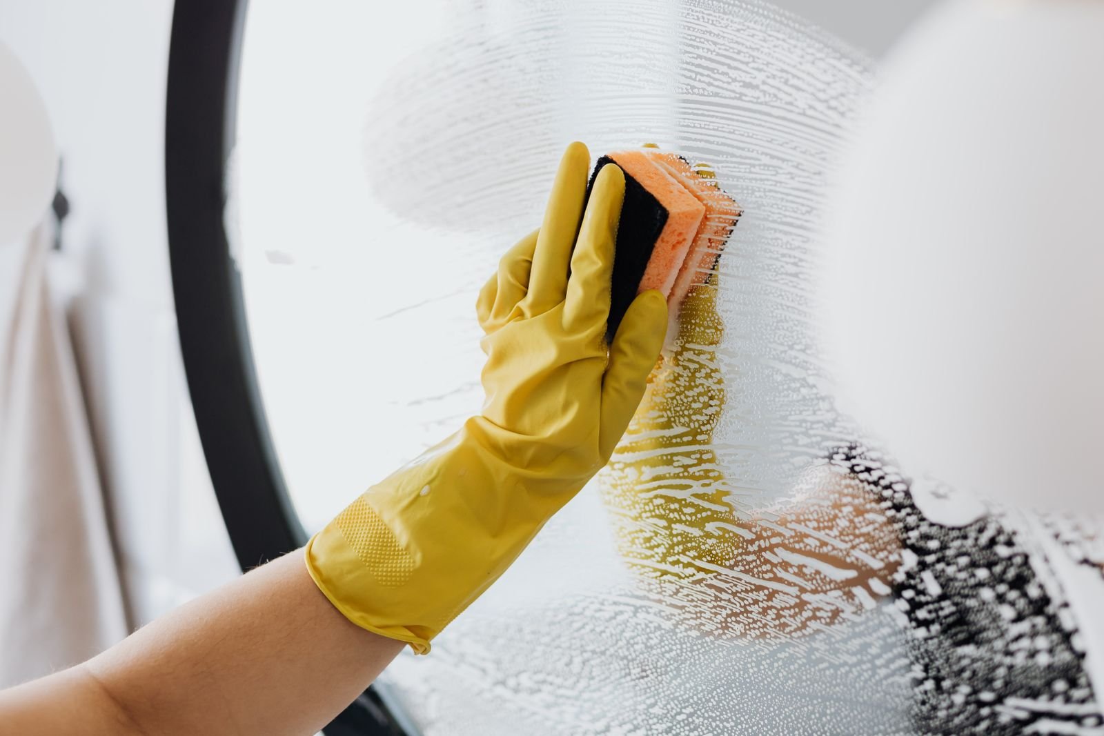 Professional cleaner scrubbing a bathroom mirror